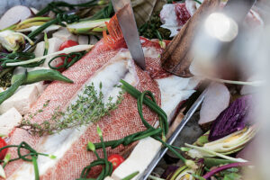 アカジンを料理。鍋の下にはサンゴを敷き、海水を少し入れ、白ワインで魚や島野菜を蒸す。サンゴで蒸すと磯の香りが立つ。